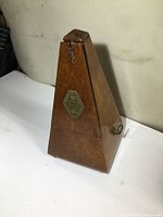 Full view of antique wooden metronome showing side and shape