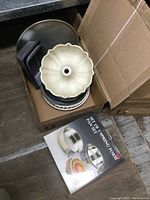 Top view of box containing a ceramic bundt pan, pie plates, cake pans, loaf pans, and a booklet for springform pans.