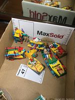 Eight Hallmark Christmas ornaments themed around Crayola crayons and toy vehicles arranged in a box showing full collection.