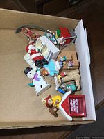 Top view of all 8 Christmas ornaments placed in a cardboard box illustrating the various characters and styles.