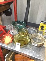 Full view of the lot showing amber chip and dip set, leaf-shaped bowl, green trifle bowl, clear glass baking dish on plated stand, glass dish with plated ring plus two clear glass pieces.