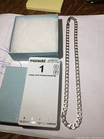 Sterling silver heavy link chain and gift box placed on surface with MaxSold card.