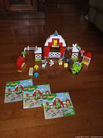 Full farm set assembled including barn, tractor, animal figures, fences, and three instruction manuals laid out in front