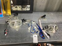 Image showing three snorkeling masks on a metallic surface: two adult and one youth-sized, each with attached snorkel tubes.