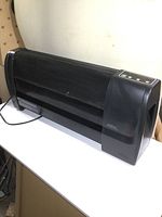 Front angled view of the Sunbeam baseboard style portable heater showing mesh grille and side controls