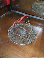 Top view of the vintage egg gathering basket showing wire mesh pattern and red handles folded down.
