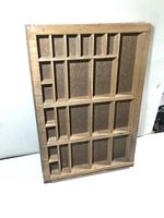 Front view of vintage wooden printers drawer showing multiple compartments and natural wood finish.