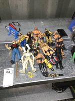 Overview of the collection showing all the wrestling figures, Batman figure, and accessories on a gray surface.