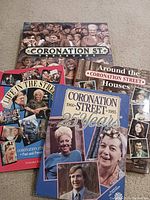 Five Coronation Street books laid out, showing title pages and cover images depicting characters and memorabilia from the TV series.