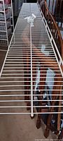 Full length view of the white metal wire shelf showing its length and grid surface.