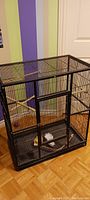 Full view of the large black metal bird cage showing structure and size in room.