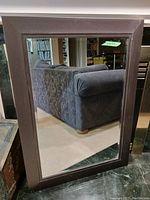 Full view of the large wall mirror showing the thick dark wooden frame and clear glass.