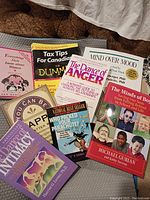 Photo showing 7 self-help books including topics on anger, intimacy, mental health, parenting, and Canadian tax tips in very good condition.