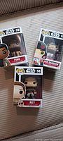 Three Funko Pop Star Wars figures Finn #59, Poe Dameron #62, Rey #58 in box displayed on surface.