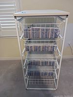 Front view of white wire storage unit with 5 drawers lined with blue and white cushioned baskets.