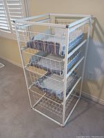 Side angled view of the white wire storage unit showing all 4 basket drawers with striped fabric liners inside.