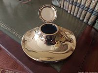 Top view of the bronze inkwell with lid open showing the ink reservoir inside.