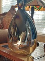 Side front view of the iridescent teardrop-shaped Sasaki Crystal vase reflecting ambient light and surroundings.