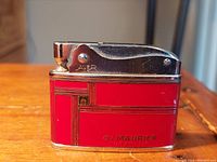 Front view of the red and silver Auer du Maurier lighter showing brand names and art deco design