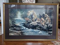 Full front view of the framed artwork showing the leopard mother and cubs near a stream in a natural environment, under glass.