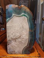 Front view of polished geode showing green and white agate layers with central quartz crystal formation.