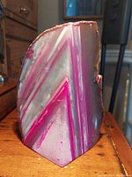 Front view of the polished triangular Brazilian fuchsia geode showing vibrant pink and white banding and rough edges.