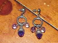 Close-up front view of the pair of vintage rope scrolled silver earrings with stone dangles.