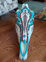Top view of the decorated horse skull with turquoise and red bead accents and hand-painted feather design