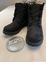 Front view of black suede Timberland boots showing both boots side by side on a table with a lot number lid in front.