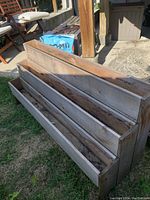 Photo showing the three-tiered cedar planter box outdoors on grass, displaying its full length, weathered appearance, and tiered structure.