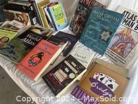 Image showing a variety of non-fiction books including a World Atlas, Water Crystal Healing by Masaru Emoto, Atlas of Man, and others, arranged on a white surface.