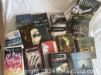 Photo showing 16 fantasy books arranged on a bed, including The Hobbit and Magyk, displaying their colorful covers and titles