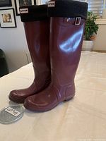 Side view of both deep burgundy Hunter rain boots with black fleece liner cuffs