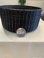 Front view of large black wicker basket on a table with lot number in front.