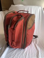 View of red and brown Apollo Walker picnic backpack front and side profile showing main compartment and zipped sections.