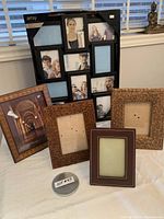 Photo showing the large black multi-photo frame and four smaller frames in front arranged on table.