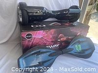 Black Swagway X1 hoverboard with original box and blue-black Ripstick board on white cloth.