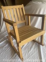 Front angle view of vintage wooden toddler rocking chair showing slatted back, armrests, and rocker base.