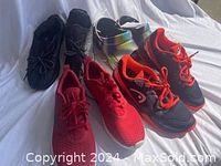 Five pairs of shoes grouped on white background: black Nike golf shoes, red athletic shoes, red/black Saucony with orange laces, multicolor Crocs, black Adidas Boost sneakers.