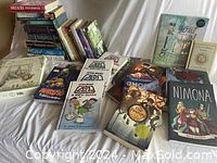 Wide view showing stacked and arranged books including Jedi Academy, Amulet, Nimona, and Girls & Sex title.