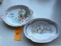 Pair of two vintage vanity/trinket/soap dishes side by side showing size and design differences with floral hand-painted decoration