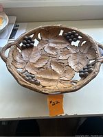 Photo of entire wood carved fruit bowl showing the grape and leaf details and the bowl shape with handles