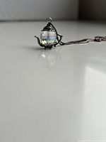 Close-up side-angle of the teapot charm necklace showing detailed crystal bead and silver metalwork