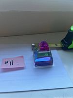 Crystal paper weight pyramid displaying vibrant internal colors with measuring tape showing base length around 2 inches.