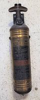 Front view of antique brass Pyrene fire extinguisher showing embossed brass body with printed instructions and branding.