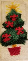Hand hooked latch hook Christmas tree panel with figures attached, featuring green tree with red bows on cream background.