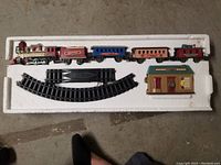 Complete train set including engine, three passenger cars, caboose, and track pieces laid out in white foam packaging.
