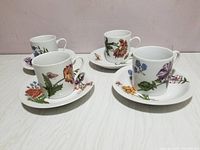 Front view of four demitasse cups on saucers each featuring distinct colorful floral patterns on white ceramic, showing only the top and sides.