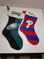 Two plush stockings: Philadelphia Eagles and Philadelphia Phillies, showing team logos and colors