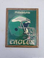 Front view showing Philadelphia Eagles helmet graphic with clock hands and team name inside wooden frame.